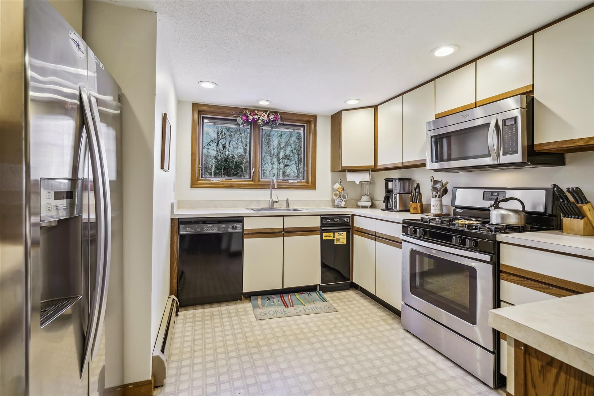 This kitchen has an electric stove, microwave, dishwasher, coffee pot.