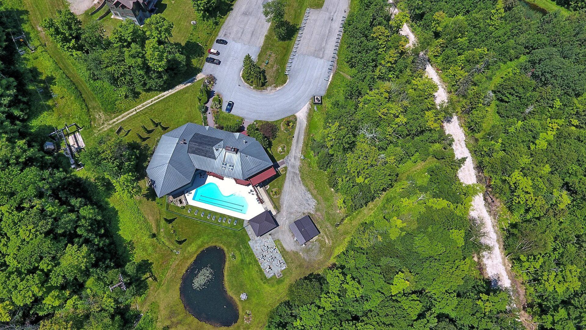 Aerial view of The Lodges surrounded by lush green mountains. The complex features outdoor pool access, scenic walking trails, and breathtaking views in every direction.