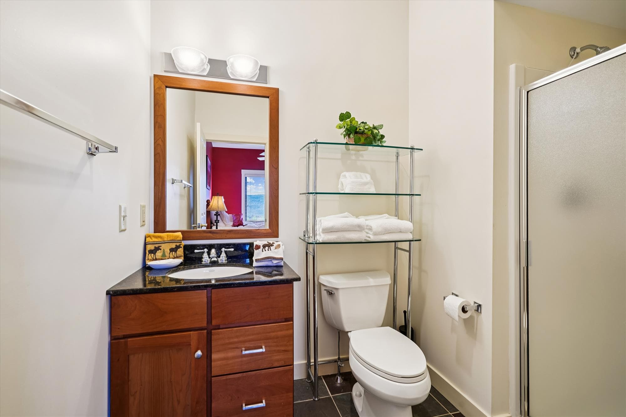 Clean and modern bath with walk-in shower, granite vanity, and open shelving. Easily accessible from the queen bedroom.