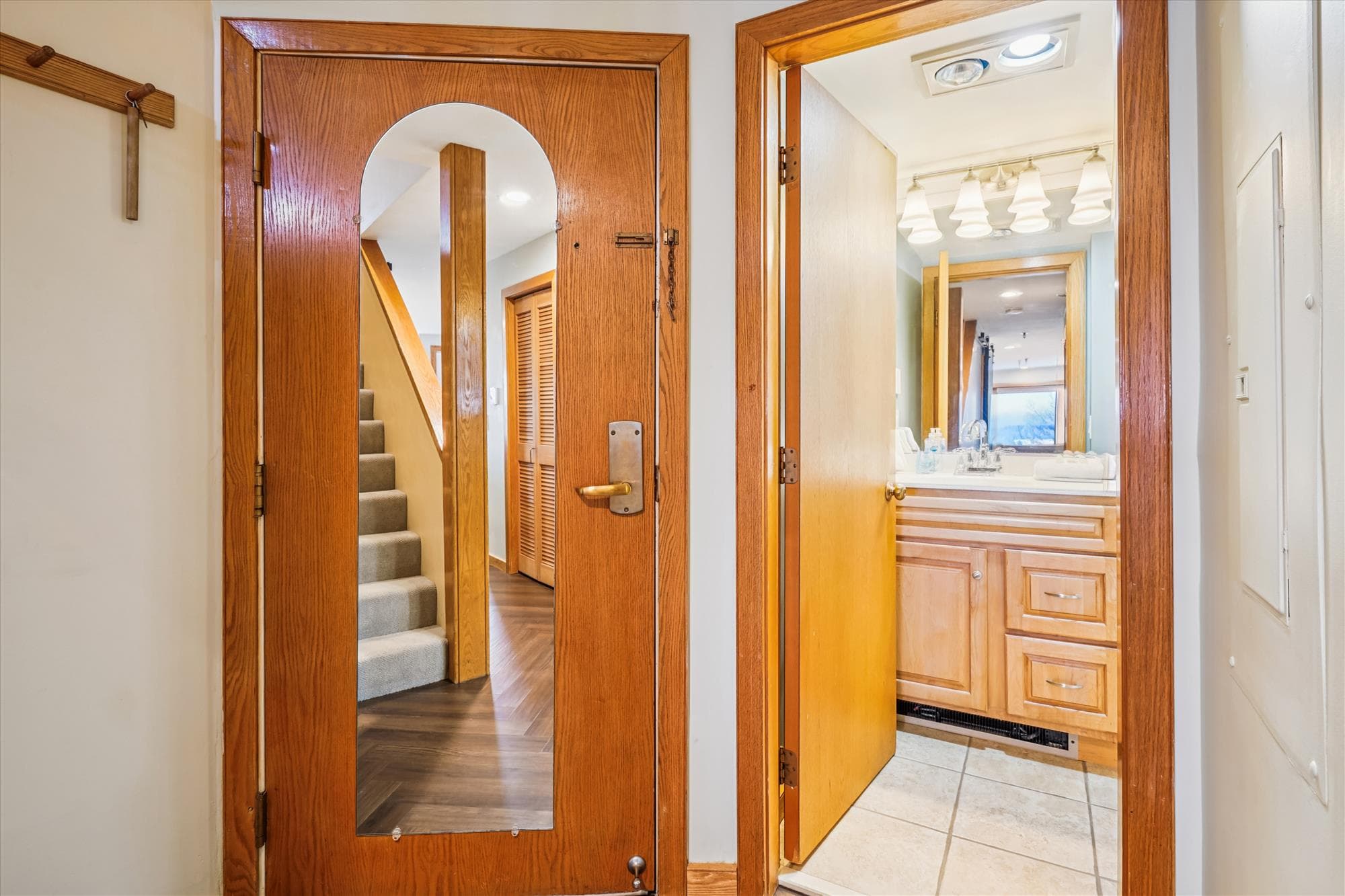 Entry hallway with access to the full bathroom and stairs leading to the upper level of the condo.