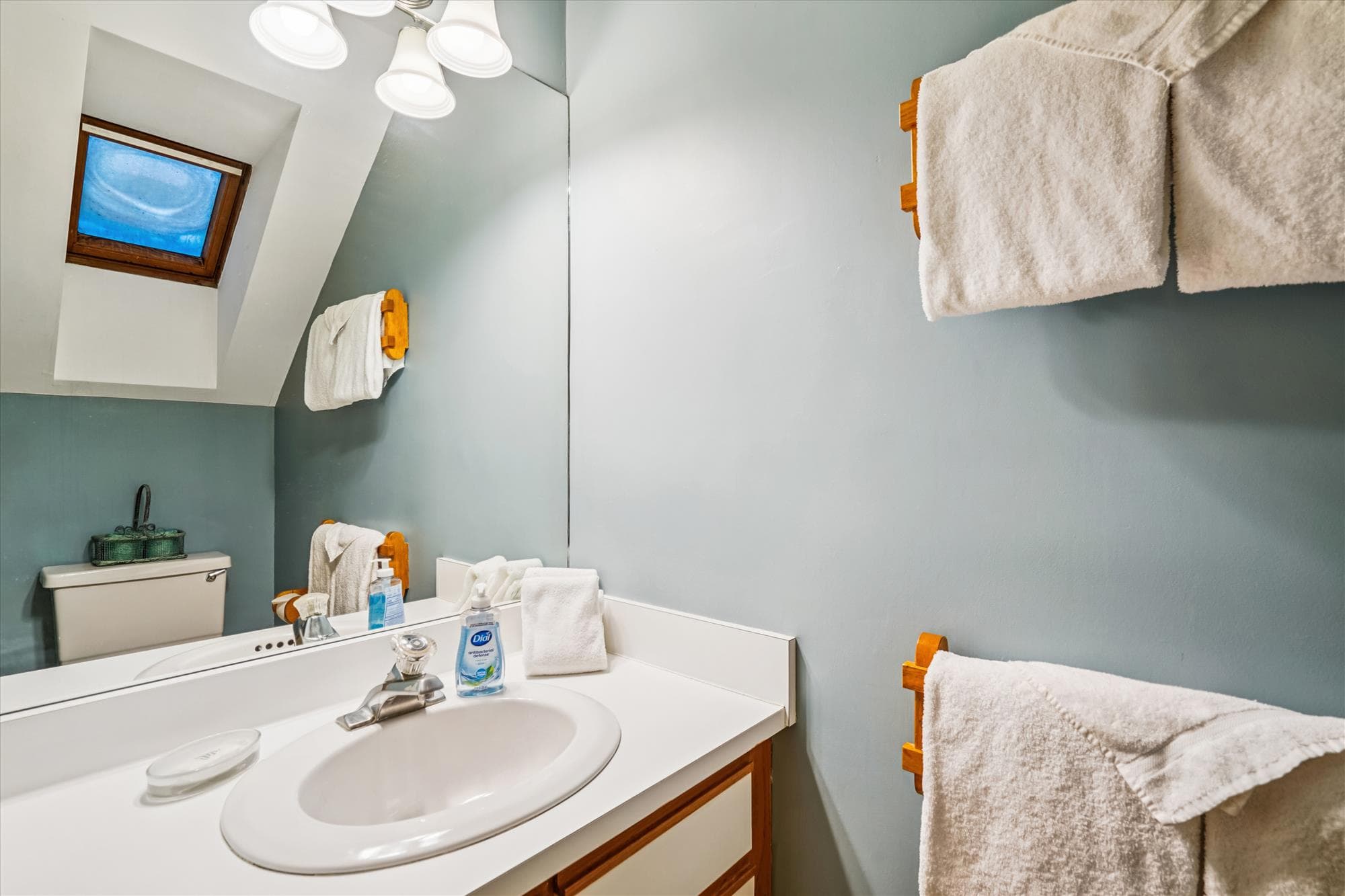 Upper level bathroom with sink, mirror, skylight, and fresh towels provided for guests.