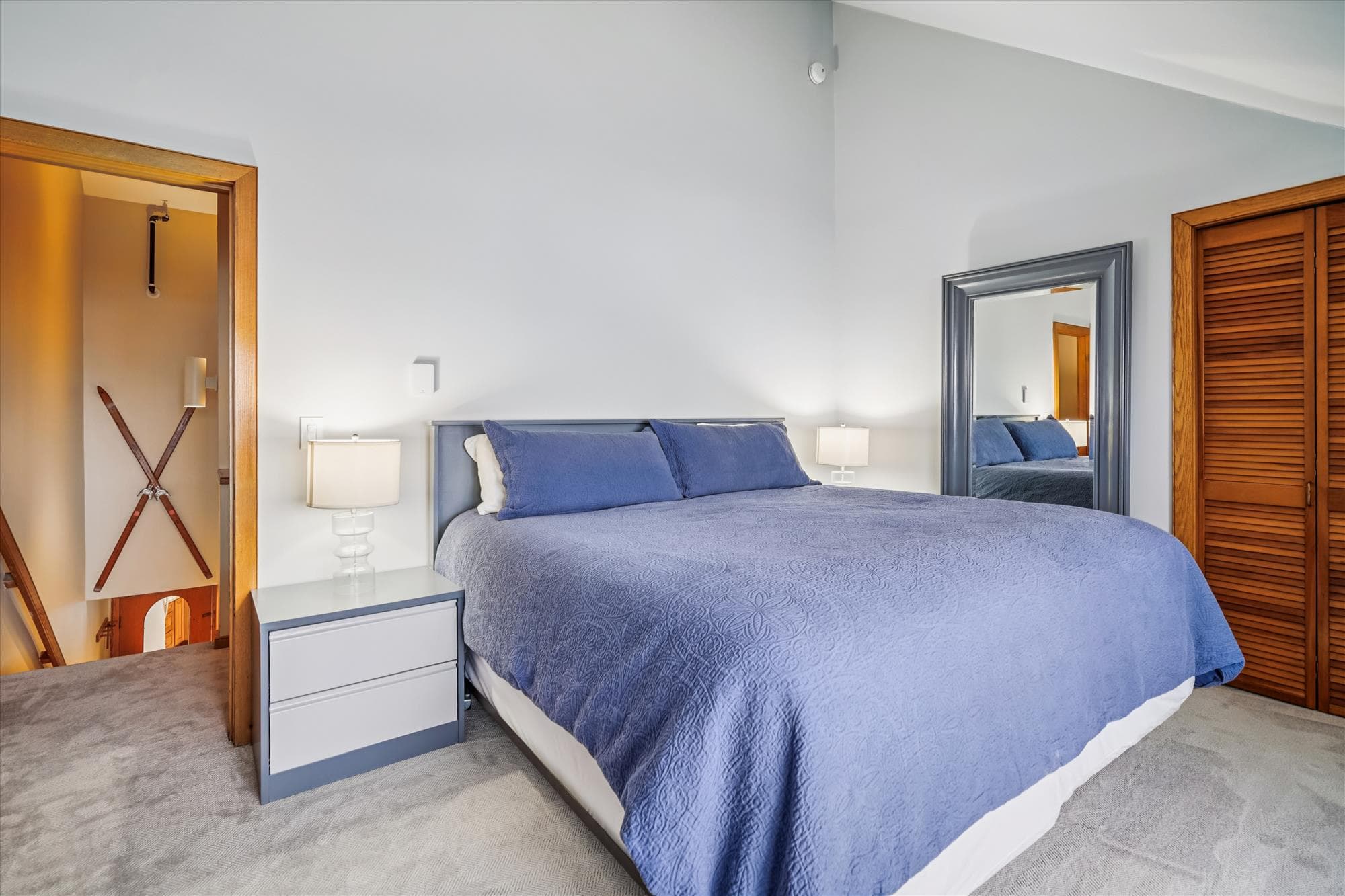 Comfortable king bedroom featuring vaulted ceilings, a lounge chair, and a small desk area by the window.