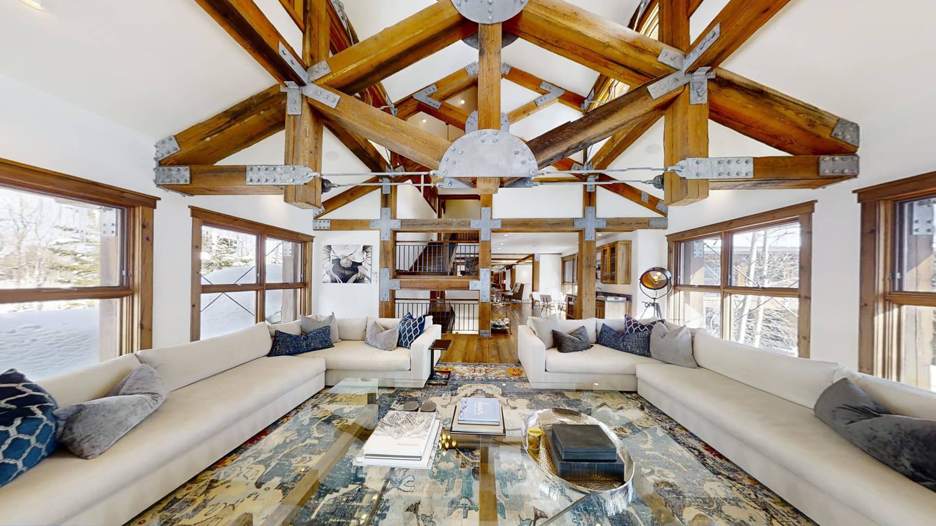 Exposed wooden roof beams highlight the living area above sectional couches.