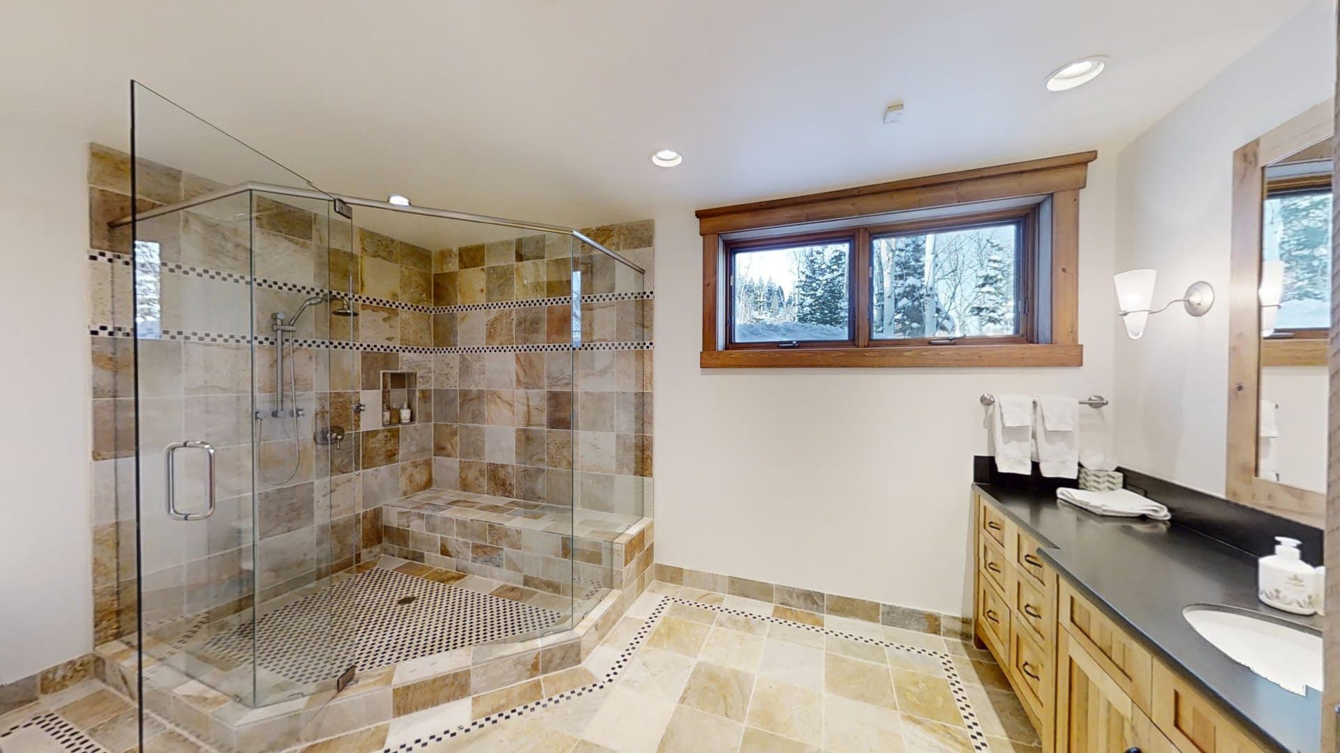 A large walk-in closet is set against the left wall of a bathroom, opposite of a long black counter.