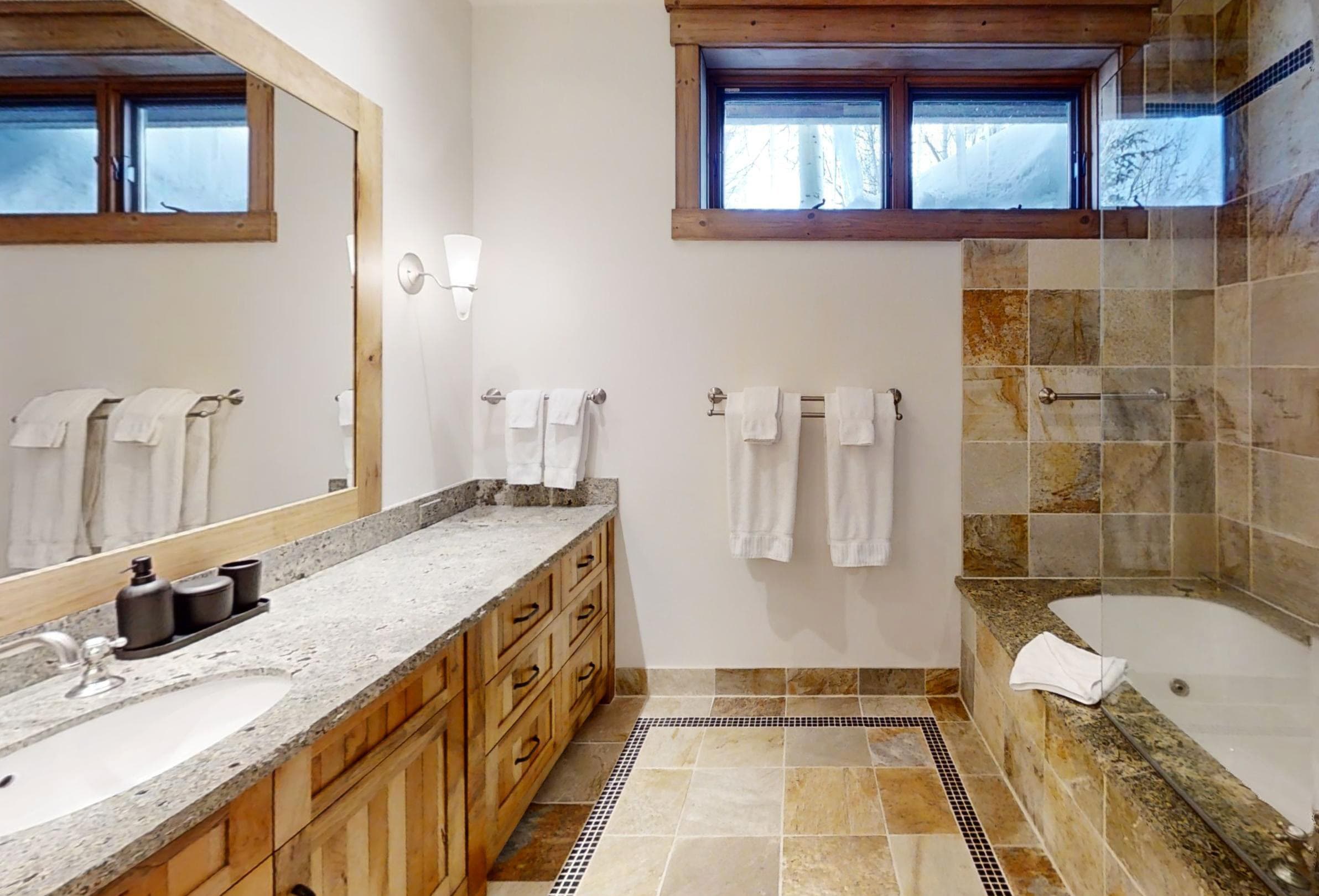 Towels hang on the wall between the large tub and sink of a bathroom.
