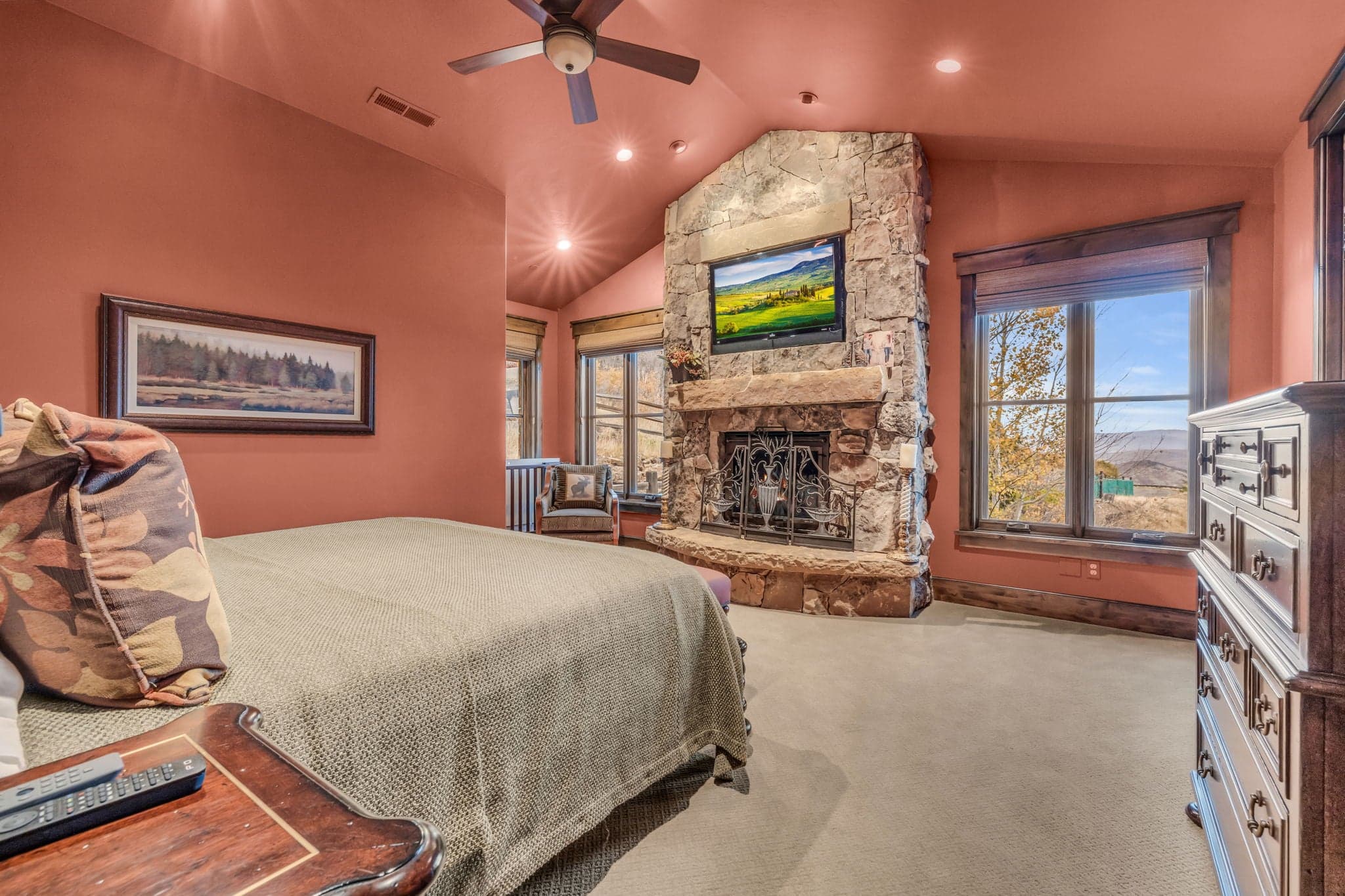 Bedroom with Queen sized mattress, chair, fireplace, dresser, nightstand and TV.
