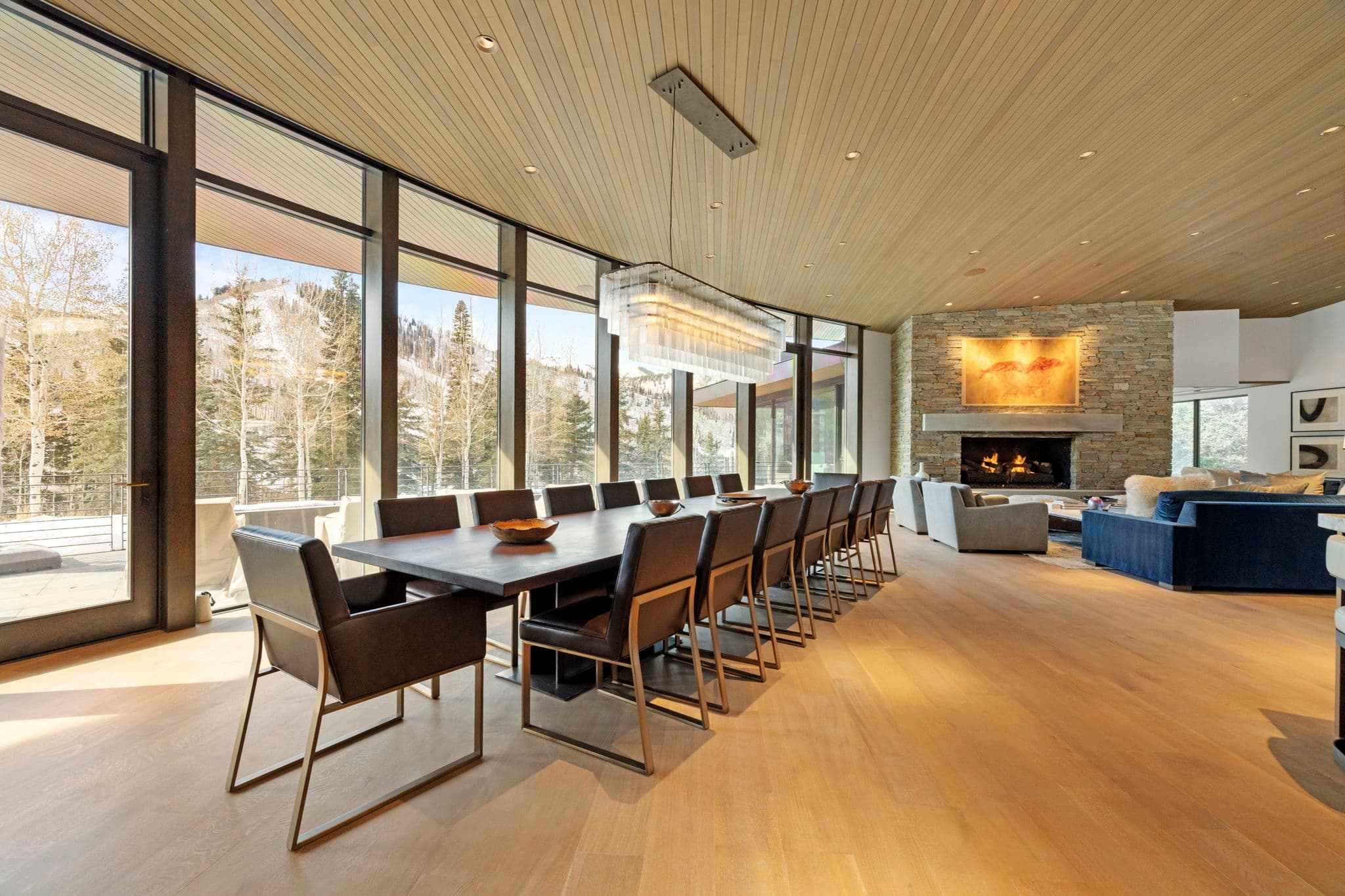 A large dining table with chairs and a chandelier above it.