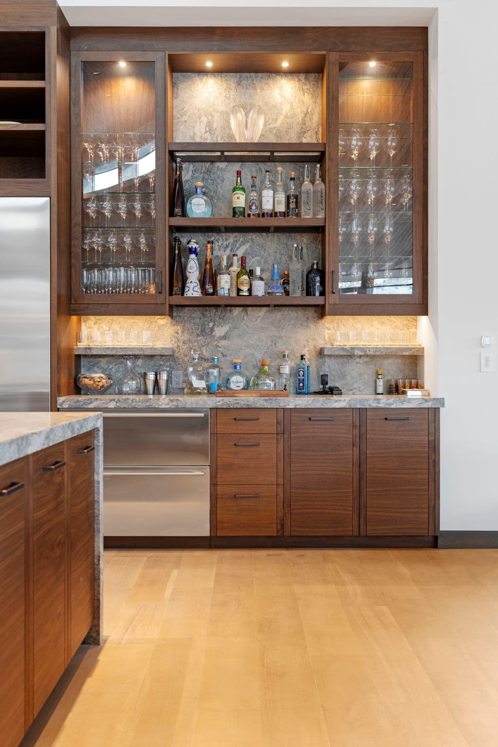 The kitchen area bar with cabinets and glassware.