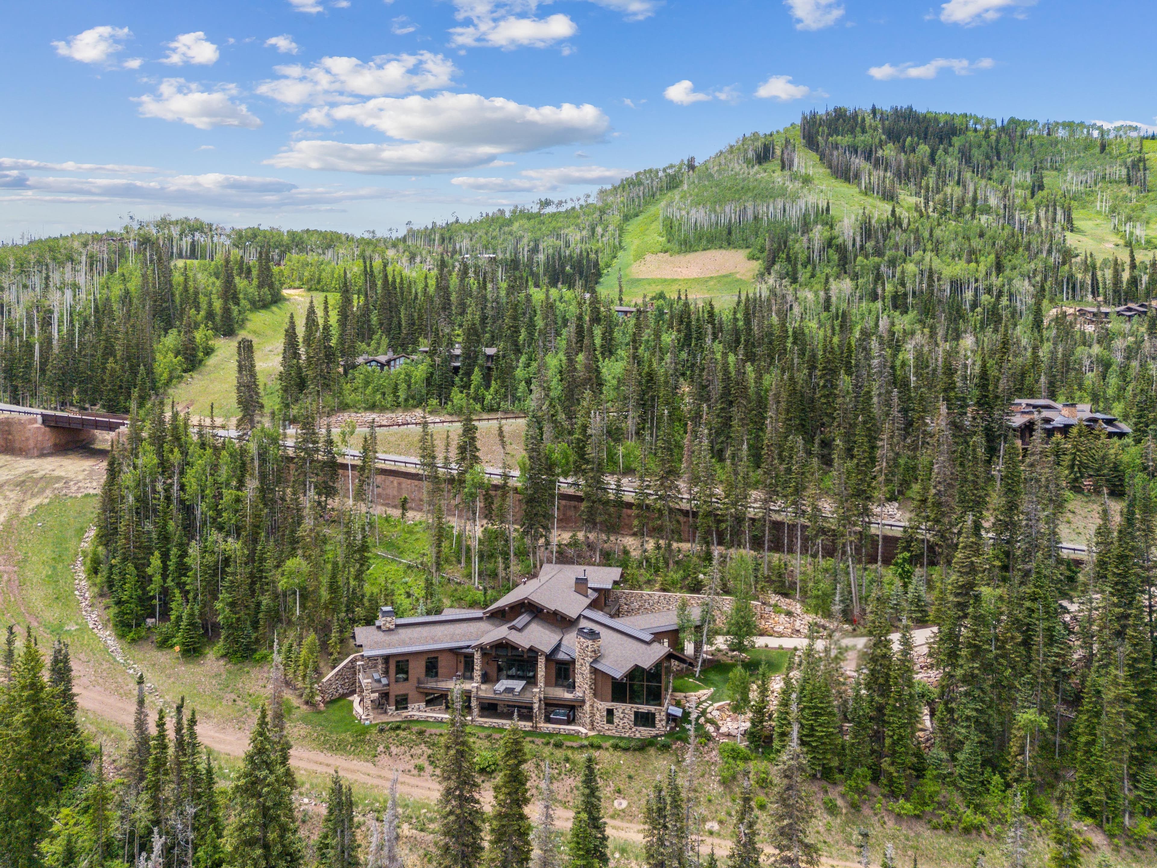 a view of Grandview with mountains in the background. ski runs are visible right in front of the home as well as on the mountains of park city behind it